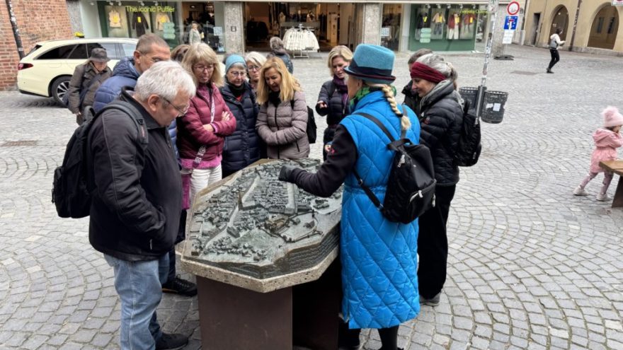 2025 10 18 KDFB Landshut RN04 - Im Oktober 2025 fuhr eine Gruppe des Frauenbund Tutzing nach Landshut. Die Stadtführerin Jutta Beer vom Tourismusbüro der Stadt empfing uns sehr herzlich. Wir gingen zunächst in den Rathaussaal, der mit Wandmalereien der Landshuter Hochzeit ausgestattet und bereits 140 Jahre alt ist. Hier wurden damals wichtige Entscheidungen getroffen. Heute finden hier Konzerte und Empfänge statt. Wir erfuhren allerlei nette Geschichten und Bräuche der damaligen Zeit, so zum Beispiel, dass die Hochzeit vor 500 Jahren die teuerste und größte mit 10.000 Gästen war, eine Woche gedauert hat und umgerechnet 20 Mio Euro gekostet hat. Die Stadt hatte Geld, da hier die Steuer und der Zoll erfunden wurden. Sie erzählte uns, dass die polnische Braut mit 18 Jahren schon zu alt war, aber der Herzog auch erst 20 war und so es ein guter Start für die Ehe war. Am Hochzeitstag gab es ein 35-Gänge Menü und wir stellten uns vor, wie man so viel Essen kann und wie man sich dabei wohl fühlt.