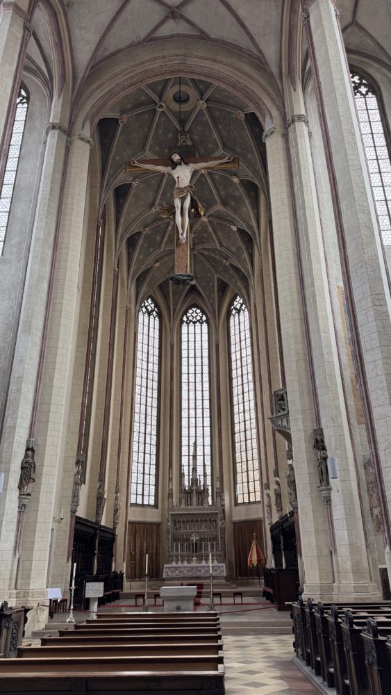 2025 10 18 KDFB Landshut RN07 - Im Oktober 2025 fuhr eine Gruppe des Frauenbund Tutzing nach Landshut. Die Stadtführerin Jutta Beer vom Tourismusbüro der Stadt empfing uns sehr herzlich. Wir gingen zunächst in den Rathaussaal, der mit Wandmalereien der Landshuter Hochzeit ausgestattet und bereits 140 Jahre alt ist. Hier wurden damals wichtige Entscheidungen getroffen. Heute finden hier Konzerte und Empfänge statt. Wir erfuhren allerlei nette Geschichten und Bräuche der damaligen Zeit, so zum Beispiel, dass die Hochzeit vor 500 Jahren die teuerste und größte mit 10.000 Gästen war, eine Woche gedauert hat und umgerechnet 20 Mio Euro gekostet hat. Die Stadt hatte Geld, da hier die Steuer und der Zoll erfunden wurden. Sie erzählte uns, dass die polnische Braut mit 18 Jahren schon zu alt war, aber der Herzog auch erst 20 war und so es ein guter Start für die Ehe war. Am Hochzeitstag gab es ein 35-Gänge Menü und wir stellten uns vor, wie man so viel Essen kann und wie man sich dabei wohl fühlt.